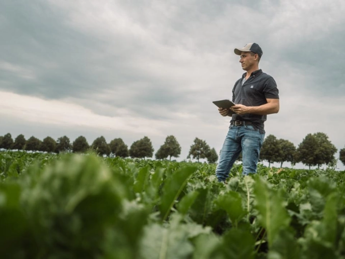 Farmer in a field holding a iPad